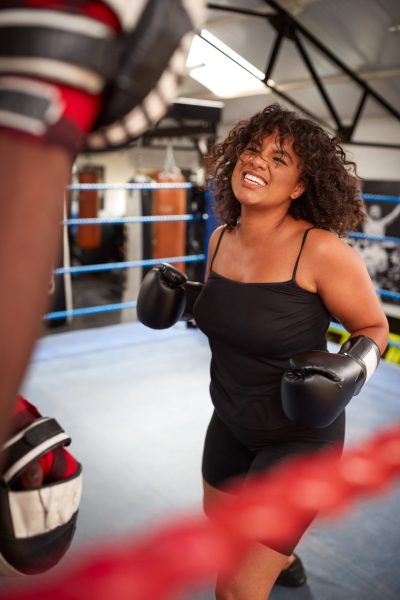 Male Personal Trainer Sparring With Female Boxer In Gym Using Training Gloves